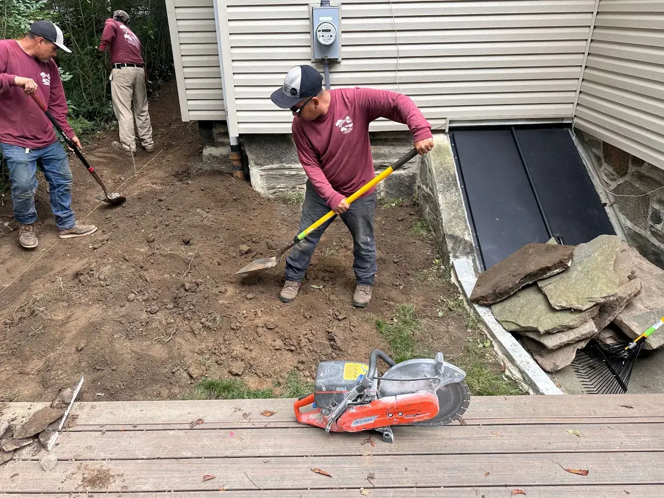 Landscaping crew excavating beside a home.