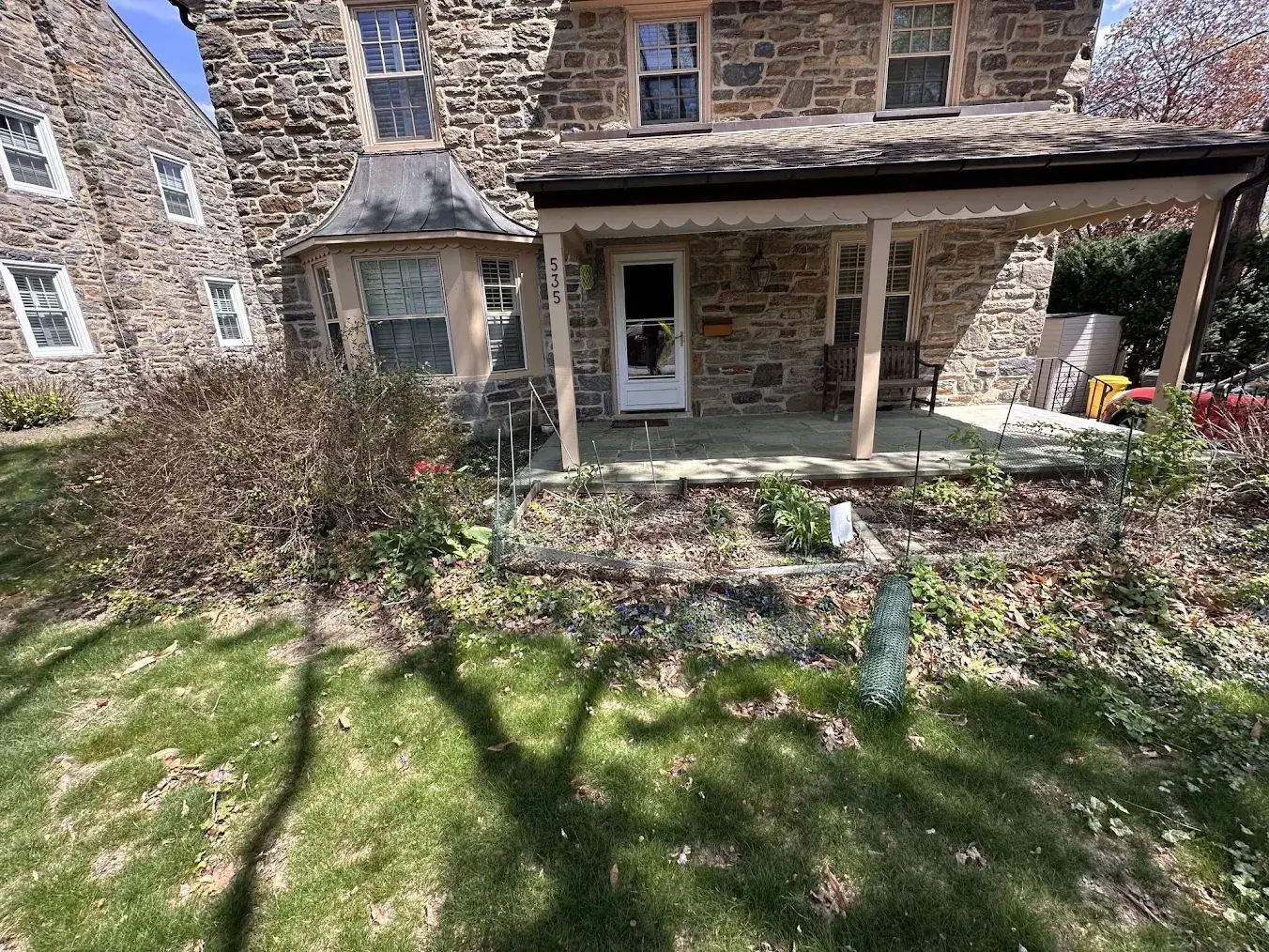 Stone home with covered front porch and garden bed.